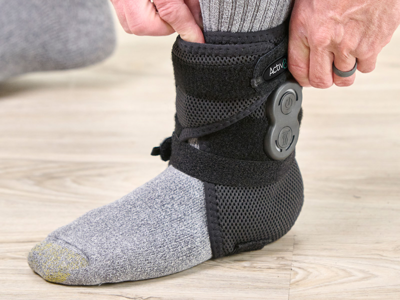 Man positioning the Activ8 Ankle device on his ankle.