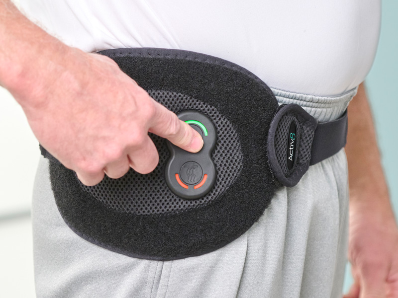 Person wearing the Activ8 Universal device around their waist, pressing a button on the controller.