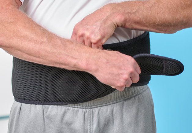 Man securing the OrthoCor Active System around his waist.