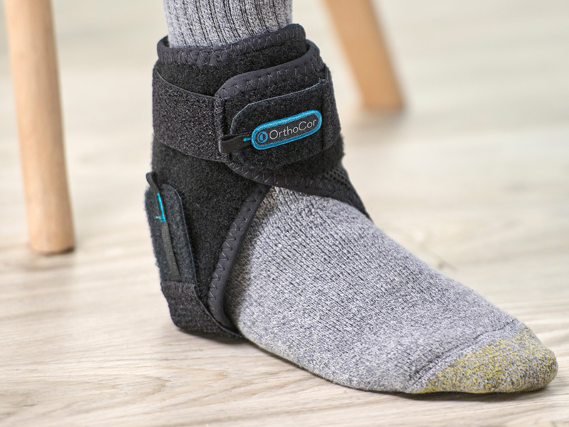 Person wearing positioning the Active Ankle device on their ankle.